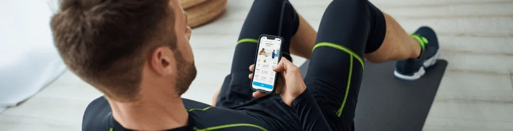 فردی در حال کار با اپلیکیشن ورزشی و دوره تمرین ورزشی در موبایل